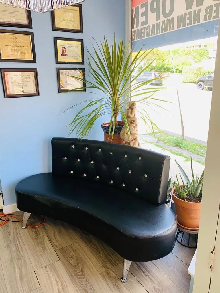 A black tufted sofa by the front window, with framed certificates and a potted palm